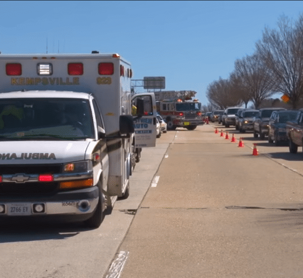 Emergency responders including an ambulance and fire truck managing a traffic incident on a highway, with orange cones separating the scene from moving traffic
